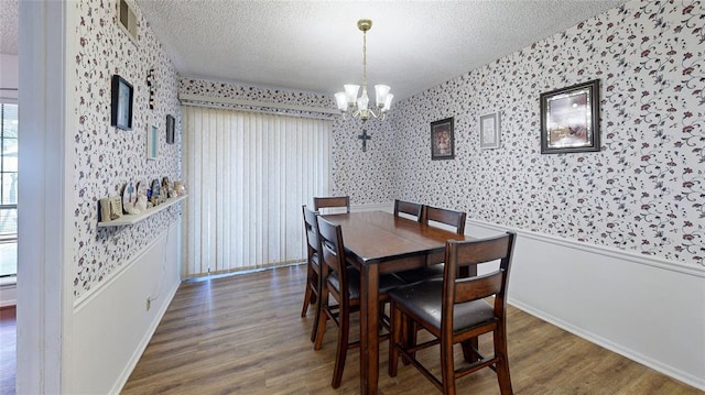 dining room with dark wood-type flooring, a chandelier, and a textured ceiling