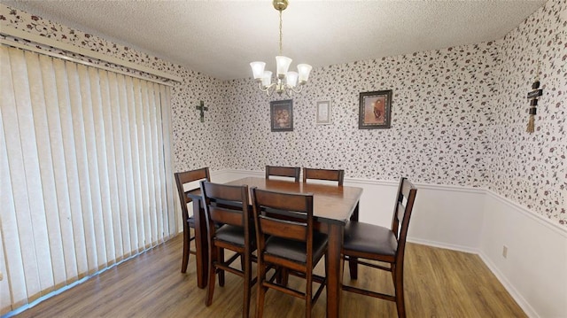 dining room with a notable chandelier, wood-type flooring, and a textured ceiling