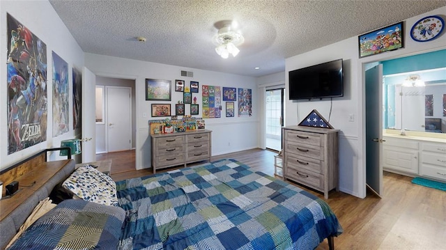 bedroom with connected bathroom, a textured ceiling, and light hardwood / wood-style flooring