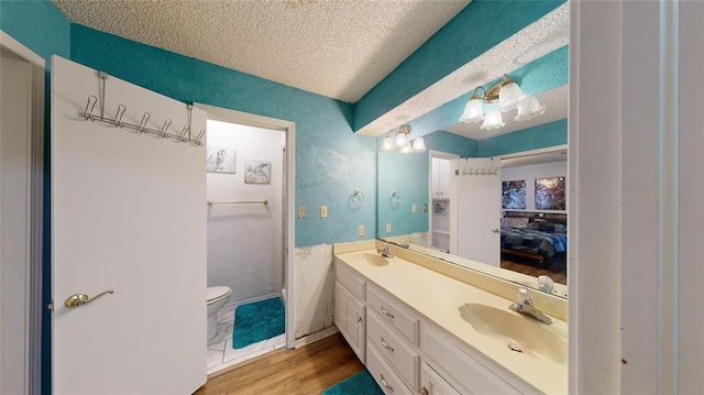 bathroom with vanity, hardwood / wood-style floors, a textured ceiling, and toilet