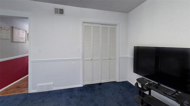 interior space featuring dark colored carpet and a textured ceiling