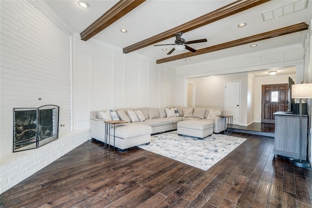 living room featuring crown molding, ceiling fan, dark hardwood / wood-style floors, a fireplace, and beamed ceiling