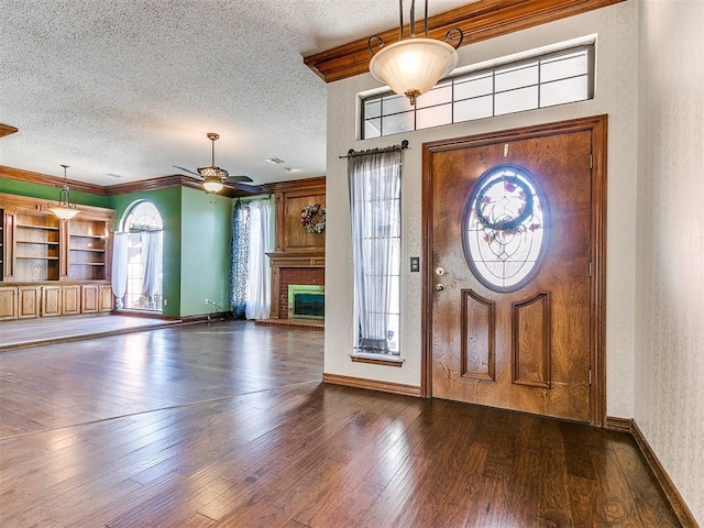 foyer with ornamental molding, dark wood-type flooring, and a textured ceiling