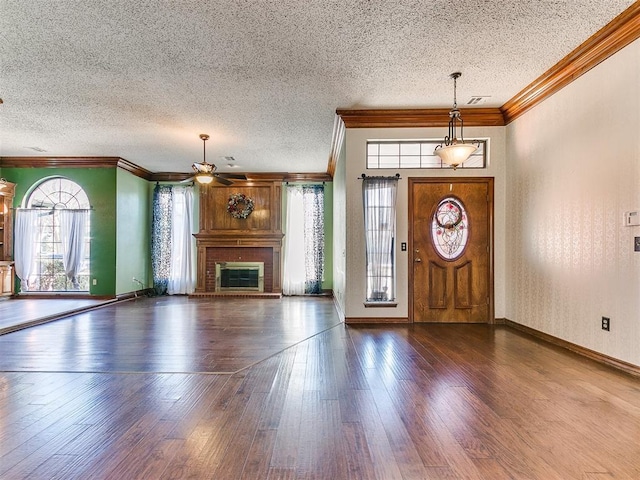 entryway with dark wood-type flooring, a fireplace, a textured ceiling, and crown molding