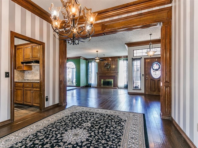 entryway featuring dark hardwood / wood-style flooring, a fireplace, ornamental molding, and a textured ceiling