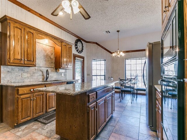 kitchen featuring sink, hanging light fixtures, a center island, black appliances, and crown molding