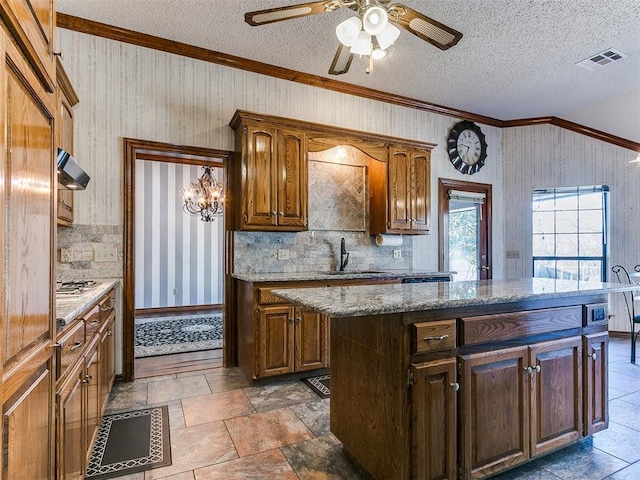 kitchen with light stone counters, sink, a textured ceiling, and a kitchen island