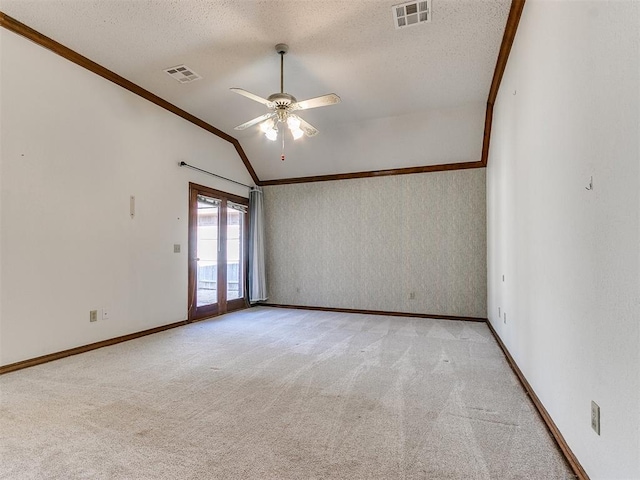 carpeted empty room featuring ornamental molding, vaulted ceiling, ceiling fan, and a textured ceiling