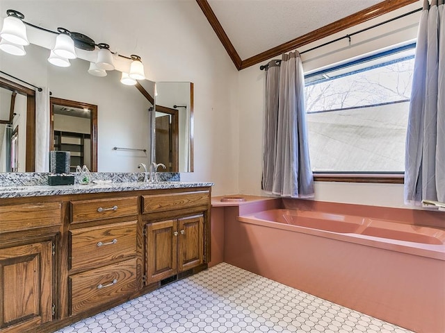 bathroom featuring ornamental molding, a bathing tub, vaulted ceiling, and vanity