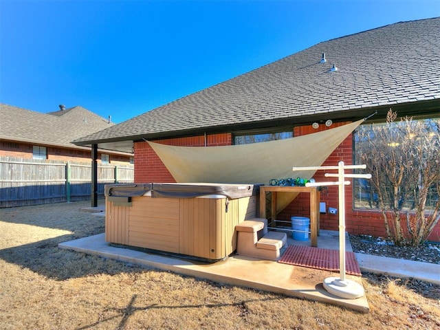 rear view of property featuring a hot tub and a patio area