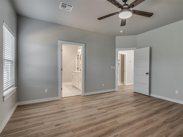 unfurnished bedroom featuring multiple windows, light hardwood / wood-style floors, and ensuite bathroom