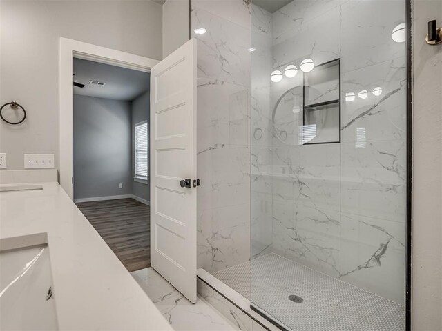 bathroom with tiled shower and vanity