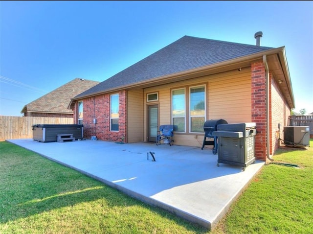 back of property featuring central AC, a lawn, a hot tub, and a patio