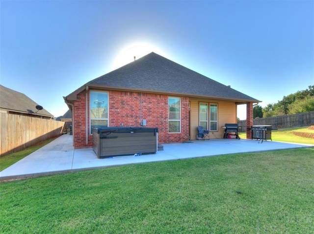 back of property featuring a yard, a hot tub, and a patio