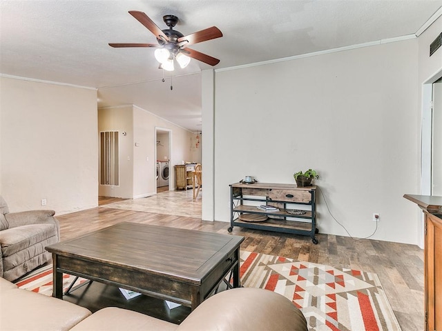 living room with vaulted ceiling, washer / clothes dryer, wood-type flooring, ceiling fan, and crown molding