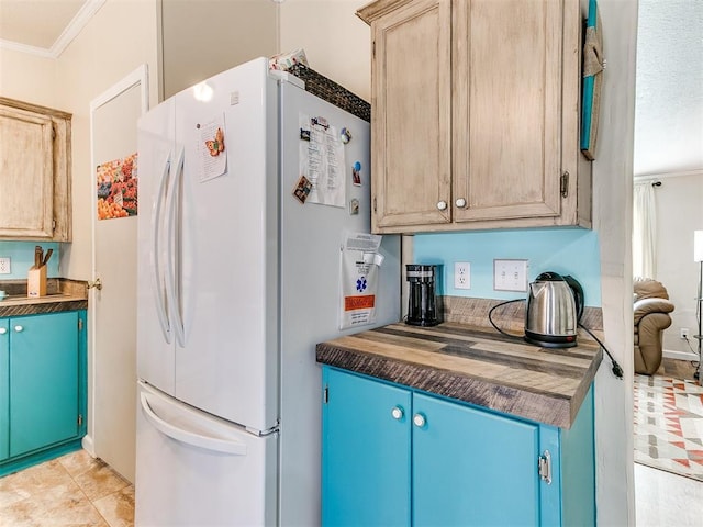 kitchen featuring white refrigerator, ornamental molding, and light brown cabinets