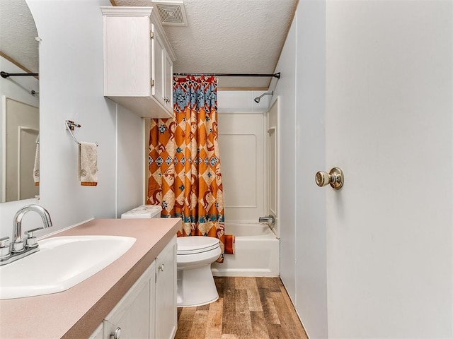 full bathroom featuring wood-type flooring, shower / bath combination with curtain, vanity, toilet, and a textured ceiling