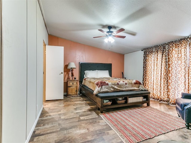 bedroom featuring vaulted ceiling, ceiling fan, a textured ceiling, and light wood-type flooring