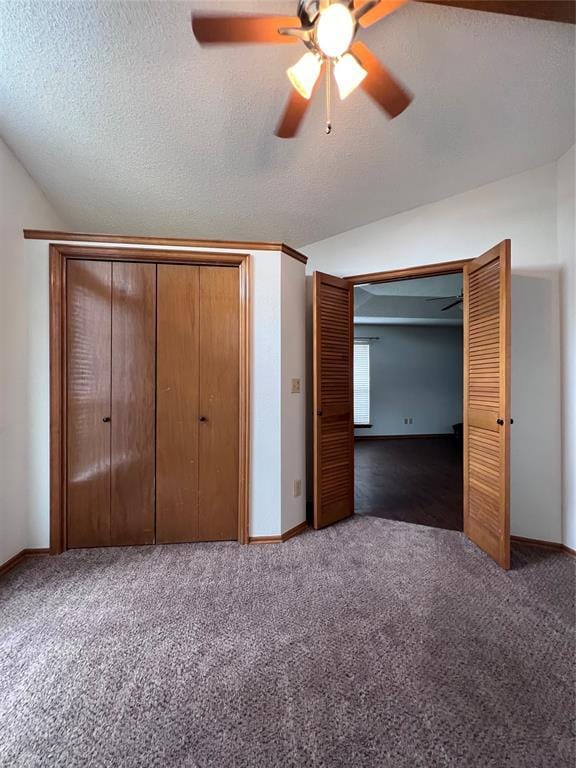 unfurnished bedroom featuring lofted ceiling, dark carpet, a closet, and a textured ceiling