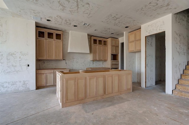 kitchen featuring a center island, wall chimney exhaust hood, and light brown cabinetry