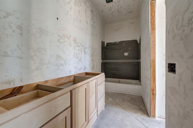 bathroom with vanity, concrete floors, and a tub