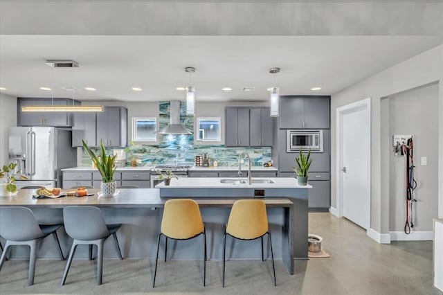 kitchen featuring gray cabinets, pendant lighting, sink, stainless steel appliances, and wall chimney exhaust hood