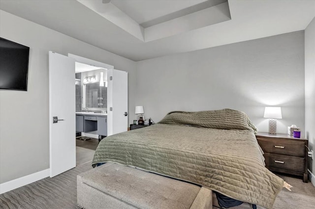 bedroom with a raised ceiling and connected bathroom