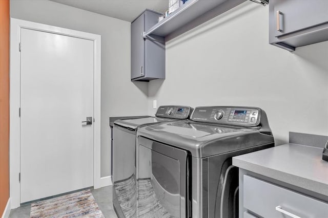 clothes washing area with cabinets and washing machine and dryer