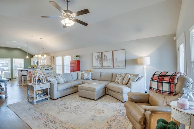 living room with ceiling fan with notable chandelier, vaulted ceiling, and light hardwood / wood-style floors