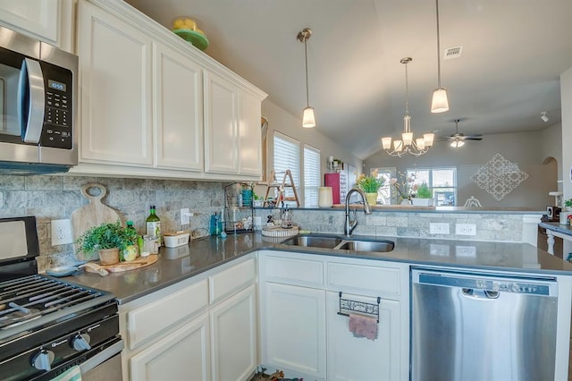 kitchen with appliances with stainless steel finishes, kitchen peninsula, sink, and hanging light fixtures