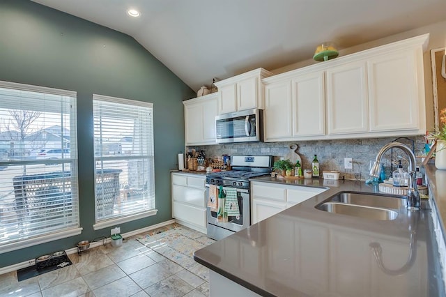 kitchen featuring lofted ceiling, appliances with stainless steel finishes, sink, and white cabinets