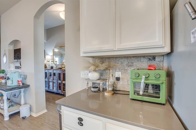 kitchen featuring white cabinetry, light wood-type flooring, and backsplash