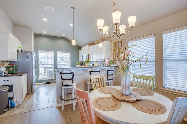 dining room with a notable chandelier, vaulted ceiling, and light hardwood / wood-style floors