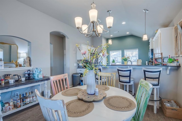 dining area featuring lofted ceiling, an inviting chandelier, and dark hardwood / wood-style flooring