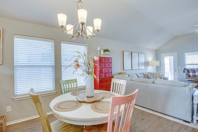 dining area featuring a chandelier, vaulted ceiling, and light wood-type flooring