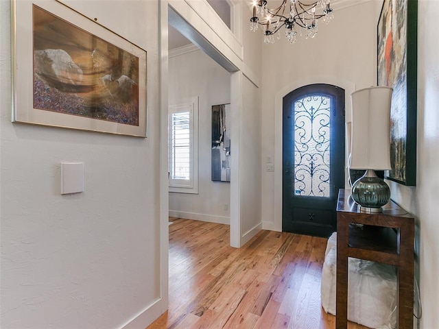 entryway with a notable chandelier, crown molding, and wood-type flooring