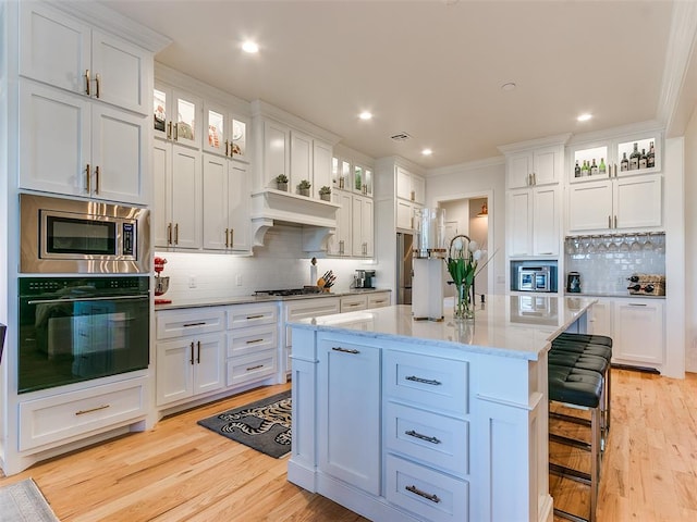 kitchen with white cabinetry, stainless steel microwave, black oven, and a kitchen island