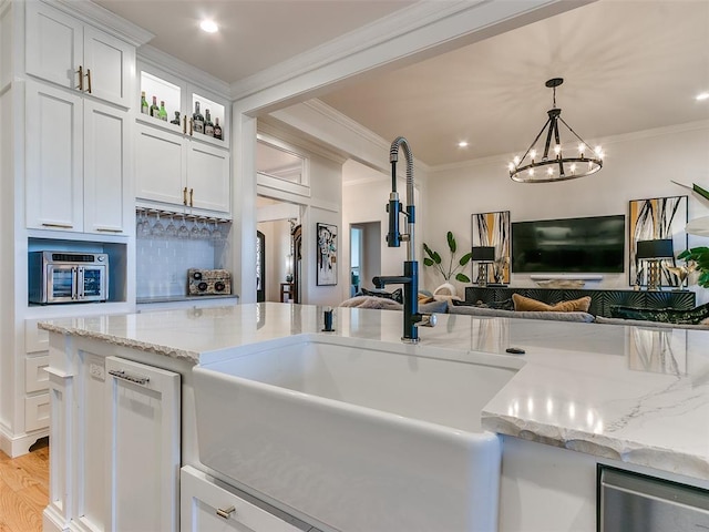 kitchen featuring sink, dishwasher, hanging light fixtures, ornamental molding, and white cabinets