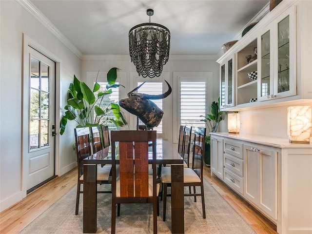 dining area featuring an inviting chandelier, ornamental molding, and light wood-type flooring