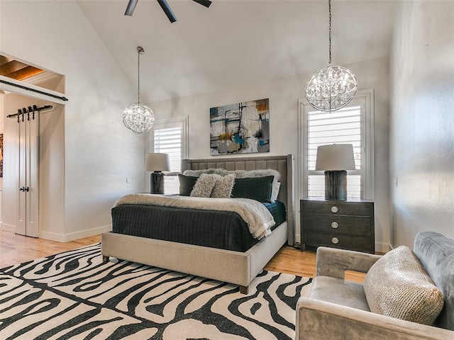 bedroom with lofted ceiling, a notable chandelier, and light hardwood / wood-style flooring