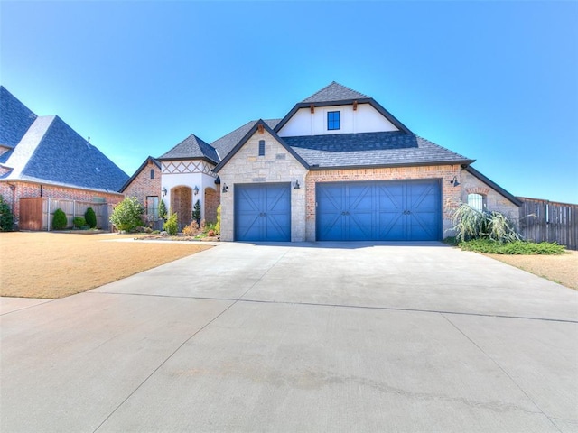 3208 Rolling Woods Dr, Norman, OK 73072 - view of front of property featuring concrete driveway, fence, stone siding, and roof with shingles