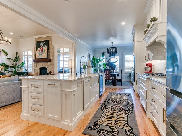 3208 Rolling Woods Dr, Norman, OK 73072 - kitchen featuring light wood-style flooring, a notable chandelier, open floor plan, and white cabinets