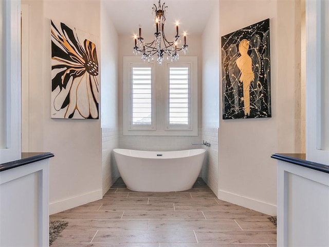 3208 Rolling Woods Dr, Norman, OK 73072 - full bath featuring wood finished floors, tile walls, an inviting chandelier, wainscoting, and a freestanding bath