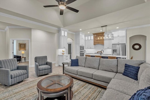 living room featuring crown molding, ceiling fan with notable chandelier, and light hardwood / wood-style flooring