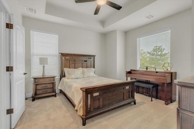 carpeted bedroom featuring a tray ceiling and ceiling fan