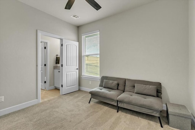 living area with light colored carpet and ceiling fan