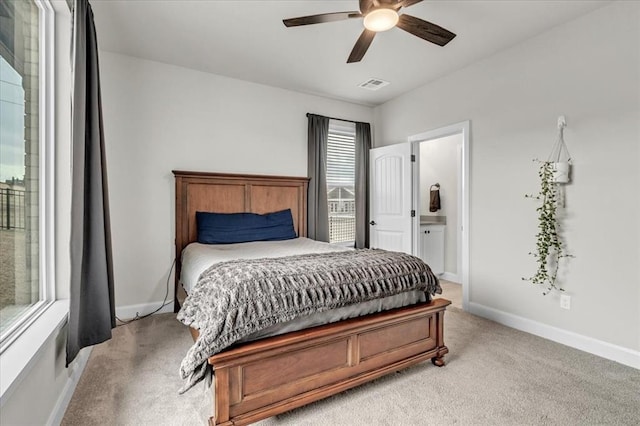 bedroom featuring light carpet, ensuite bath, and ceiling fan