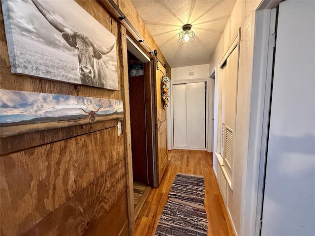 corridor featuring hardwood / wood-style flooring and a barn door