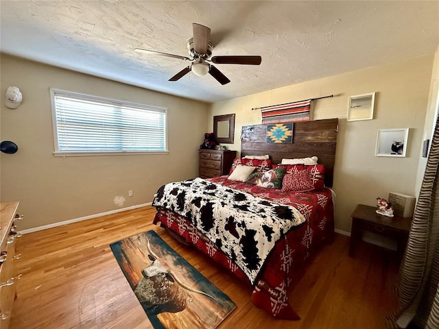 bedroom with wood-type flooring, ceiling fan, and a textured ceiling