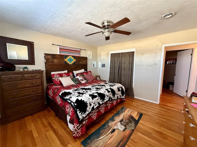 bedroom featuring ceiling fan, light hardwood / wood-style floors, a closet, and a textured ceiling